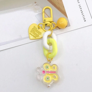 Détail d'un porte-clés cœur jaune avec breloque papillon et grosse chaîne résine