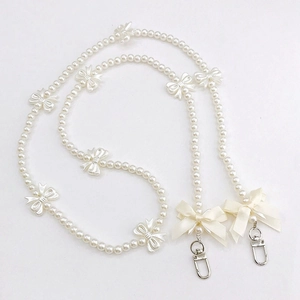 Detail of pearl phone strap with 3D bows and silk ribbon accents on white background