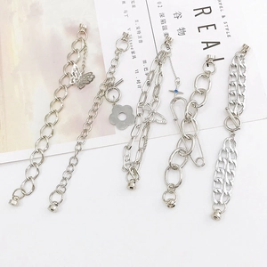 Bracelets à chaîne en métal argenté avec breloques papillon et croix sur fond de magazine
