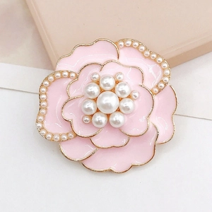 Détails d'un accessoire camélia rose avec bords dorés et accents de perles