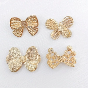 Lot de quatre breloques dorées en forme de nœuds et papillons pour créations DIY