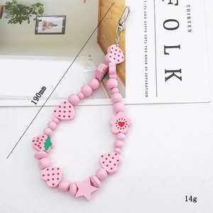 Detailed view of pink beaded charm with strawberry and heart shapes on white desk