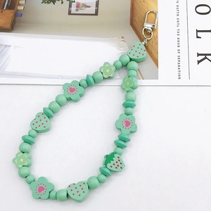 Detail of mint green strawberry charm and patterned beads on a silver metal spring clasp