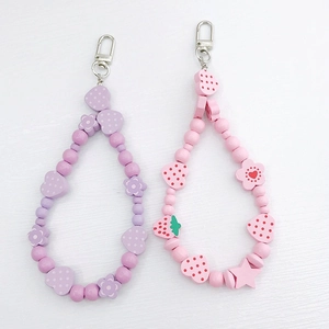 Detail of colorful fruit-themed beaded charms with heart and flower shapes on lobster clasps