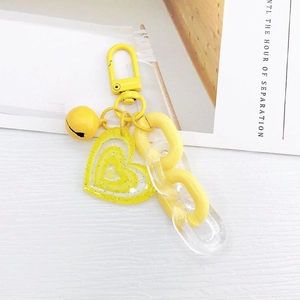Gros plan du porte-clés coeur jaune en acrylique avec clochette et chaîne à maillons
