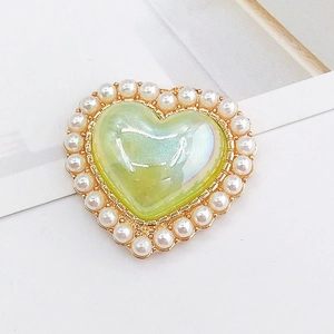 Macro view of vintage heart charm with iridescent stone and pearl border for DIY