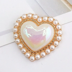 Macro detail of heart-shaped pearl charm with iridescent gemstone in gold frame