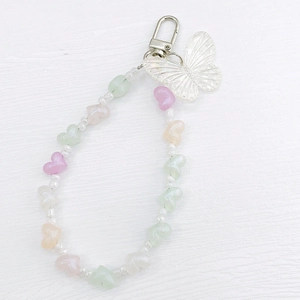 Close-up of macaron resin heart beads with a colorful butterfly charm and metal clasp