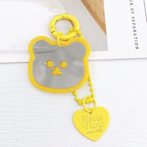 Gros plan du porte-clés miroir ours jaune avec breloque cœur Mezzo Piano sur bois