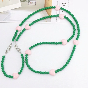 Detailed macro view of green round beads and pink heart charms with metal clasps