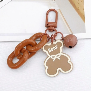 Close-up of brown acrylic bear keychain with matching small bell and plastic chain
