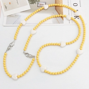 Close-up of colorful acrylic heart beads and yellow rounds on a crossbody chain