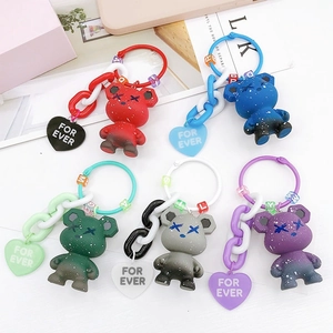 Colorful matte candy bear keychains with paint splatter and plastic chains on a desk