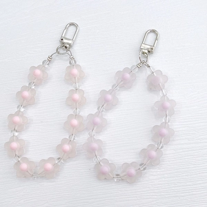 Close-up of frosted flower beads and clear acrylic charms on a silver metal keychain