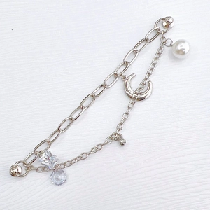 Détail d'un bracelet double chaîne argentée avec lune et breloques en zircone