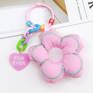 Détail d'un porte-clés fleur en tissu rose avec chaînes colorées et perles alphabétiques