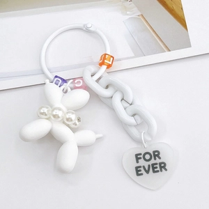 Detail of white balloon dog keychain with pearl collar and colorful letter beads