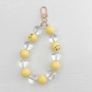 Macro shot of handmade acrylic keychain with yellow smiley face beads and gold lobster clasp