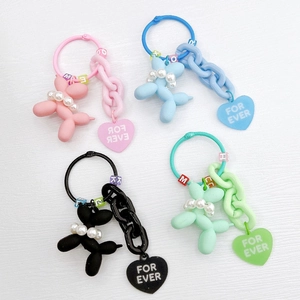 Detail of four colorful resin balloon dog keychains with pearls and heart charms