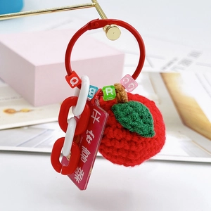 Detail of crochet apple charm with beads and a lucky tag hanging on a metal stand
