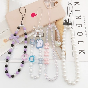 Flat lay of colorful beaded phone lanyards with bear and bow charms on a pink smartphone