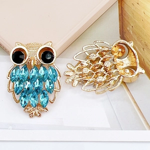 Broche de búho de cristal dorado con diamantes azules y detalle de cierre de seguridad