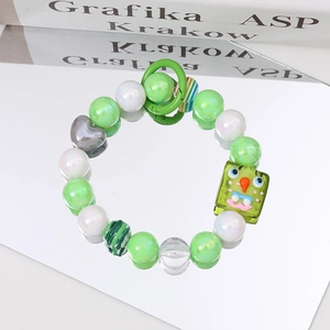 Detail of handmade beaded bracelet with green monster pendant and pearl accents