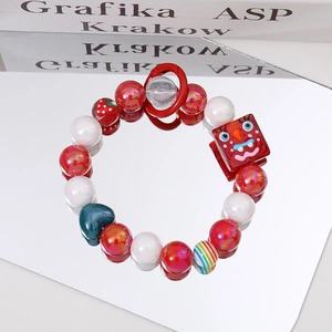 Close-up of colorful beaded bracelet with strawberry and funny square face charms