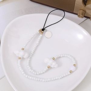 Détail de la dragonne de téléphone perlée avec nuages blancs et perles dorées en plateau