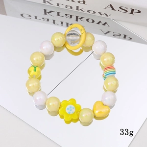 Sweet yellow beaded bracelet with sunflower and rainbow pendants on a reflective mirror