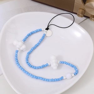 Détail de la dragonne de téléphone faite main en perles bleu ciel et nuages blancs