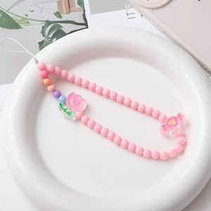 Close-up of pink acrylic beads mobile strap featuring tulip and candy charms on a white tray