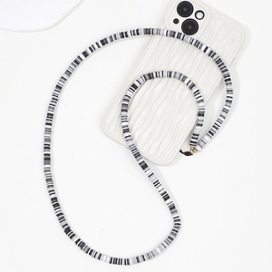 Détail du long cordon de téléphone en perles d'argile rayées avec accents métalliques dorés