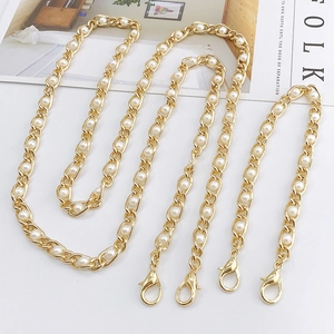 Detail of elegant gold metal chain strap with white pearls and lobster claw clasps