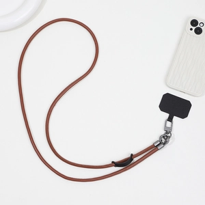 Detail of a brown leather phone lanyard with gunmetal buckle and black tether pad