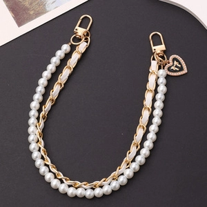 Detail of woven faux pearl and gold metal phone chain with heart bow pendant