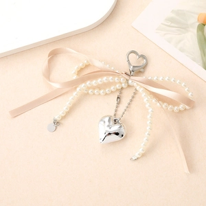 Elegante llavero de lazo con perlas con colgante de corazón y cinta en tono crema