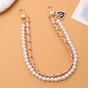 Detail of pink leather woven chain and pearl strap with black heart bow charm