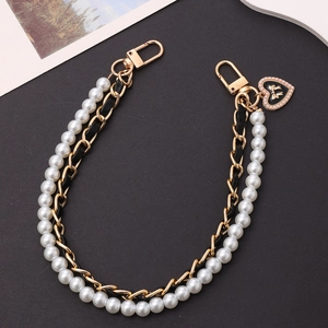Elegant pearl and gold chain strap with heart pendant on a black textured background