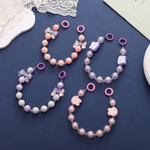 Detail of candy-colored acrylic bead chains with butterfly and bear charms in pink and purple