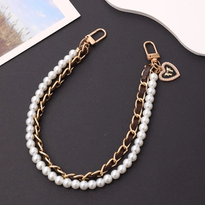 Detail of leather chain and pearl strap with heart charm and bow for phone or bag