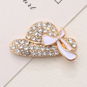 Elegant gold sun hat brooch with sparkling rhinestones and white enamel bow detail
