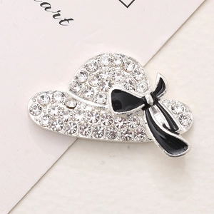 Detailed macro view of a silver hat charm with clear crystals and a black enamel bow