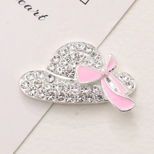 Macro shot of silver alloy straw hat brooch with clear crystals and pink enamel bow