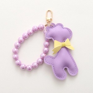 Détail d'un porte-clés caniche en PU lavande avec texture croisée et perles nacrées