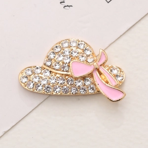 Detailed close-up of a crystal-studded straw hat charm with a pink bow decoration