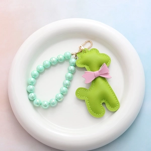 Détail du porte-clés caniche en cuir vert avec perles irisées et mousqueton doré