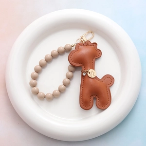 Détail d'un porte-clés girafe en cuir marron avec perles mates et finitions dorées