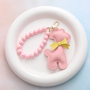 Porte-clés girafe en cuir rose avec perles nacrées et anneau doré dans une coupelle