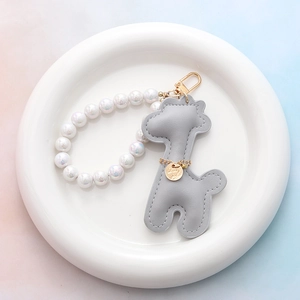 Détail du porte-clés girafe en cuir gris avec perles et étiquette Lucky Girl en métal